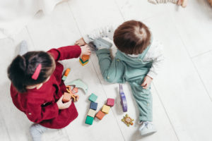 two children playing on floor with blocks