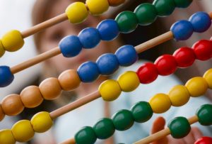 child playing with abacus with primary colored beads