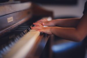 hands playing a wooden piano