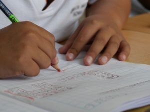 middle school student doing math equations on paper with pencil