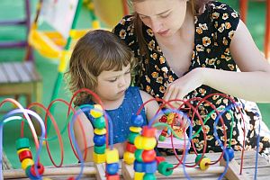 female teacher working with toddler on abacus