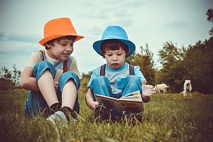 two small children reading books outside